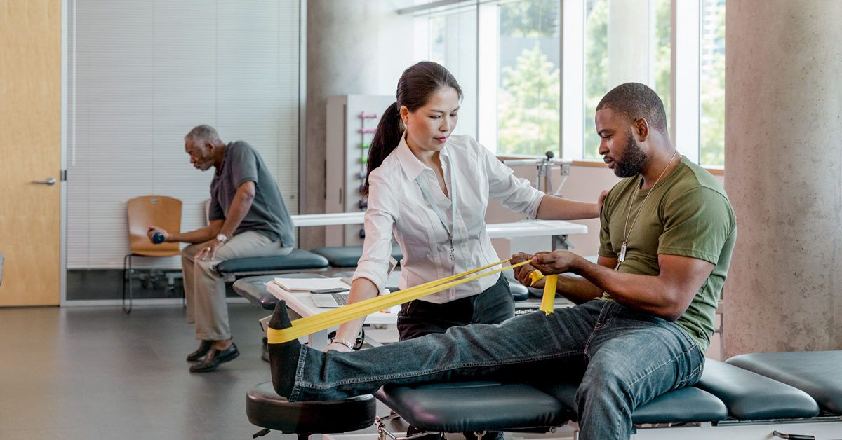 African American male uses a yellow resistance band in rehab center 1200x628 facebook