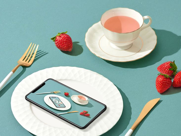 'a phone on a plate with a cup of tea and strawberries'