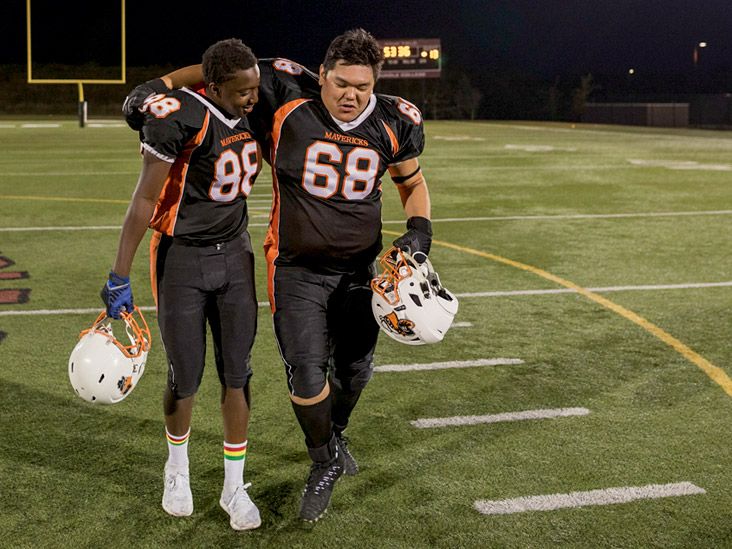 'two football players walking on a field'