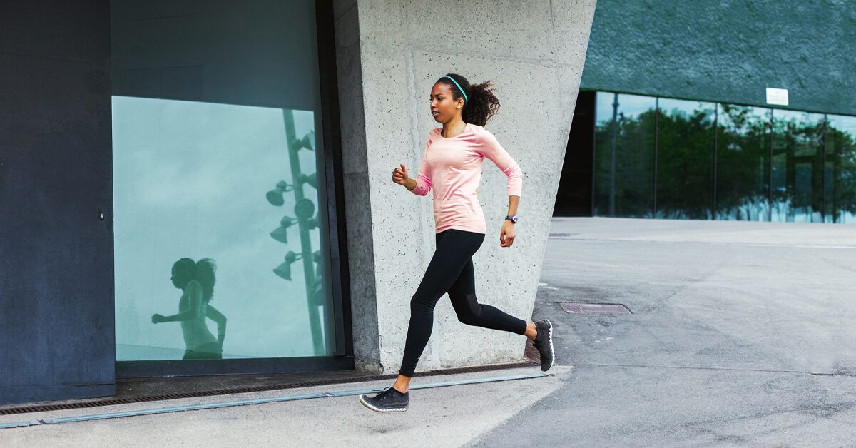 A strong athletic, female sprinter, running at sunrise wearing in