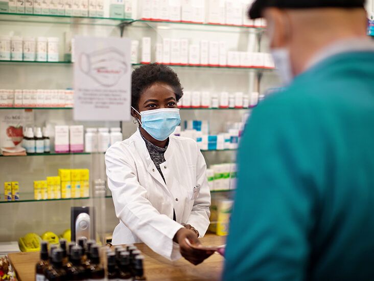 Healthline illustration of a woman customer and a woman pharmacist in friendly conversation at the pharmacy counter, warm tangerine palette
