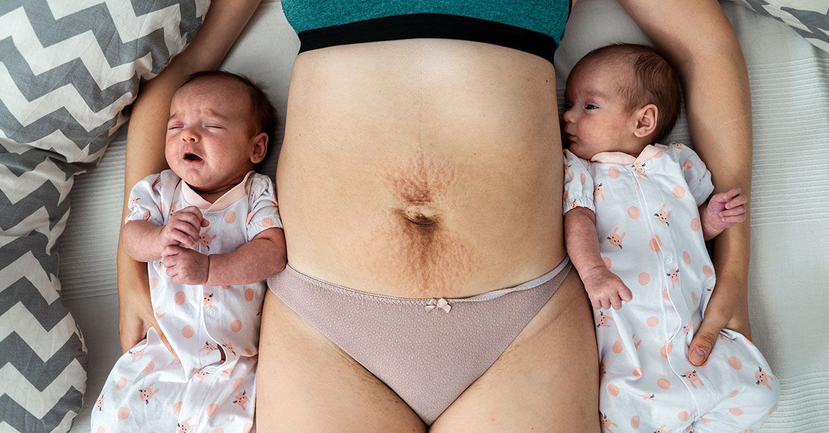 https://media.post.rvohealth.io/wp-content/uploads/2022/06/female-postpartum-on-bed-with-babies-1200-628-facebook-1200x628.jpg