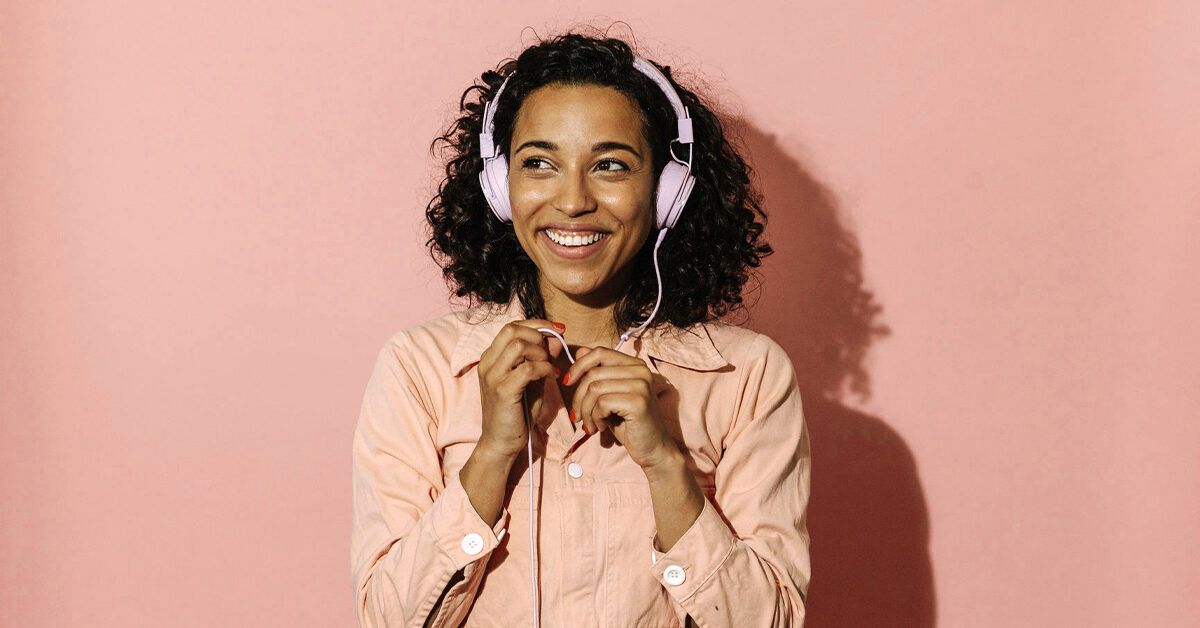 https://media.post.rvohealth.io/wp-content/uploads/2022/07/happy-woman-headphones-pink-african-american-1200x628-facebook-1200x628.jpg