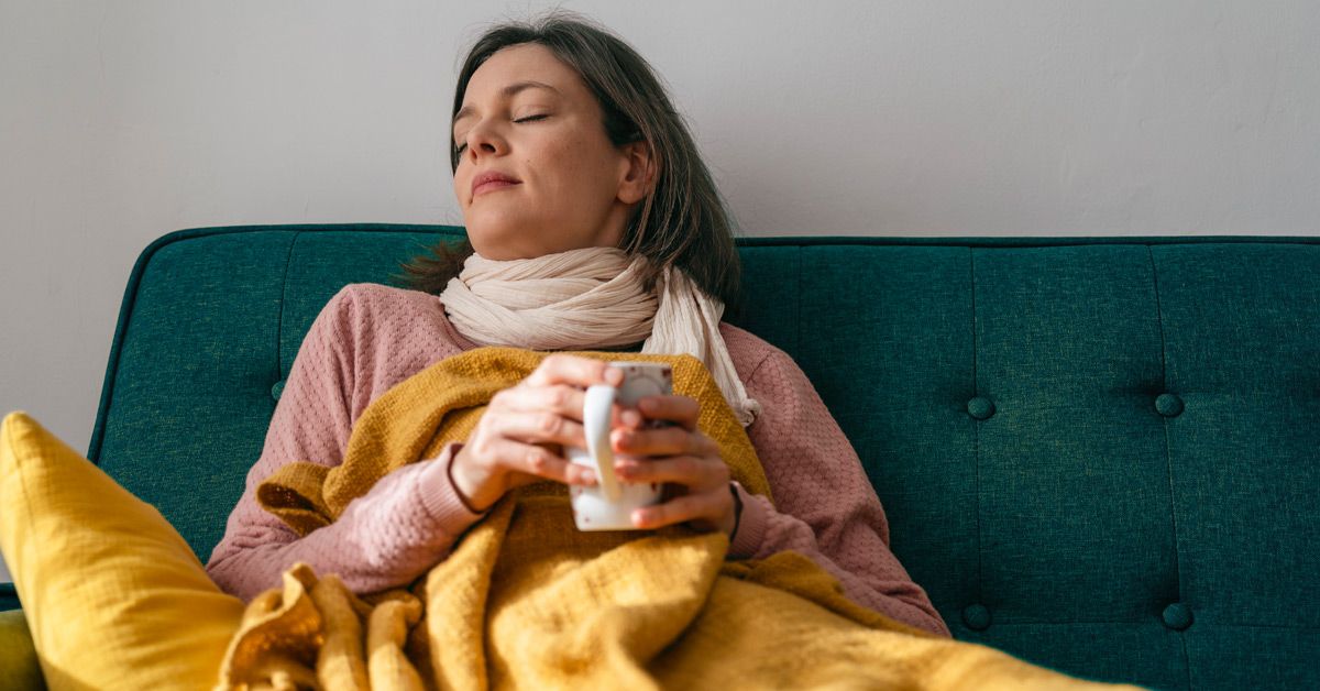 https://media.post.rvohealth.io/wp-content/uploads/2022/07/woman-feeling-unwell-at-home-on-couch-drinking-warm-liquid-1200x628-facebook.jpg