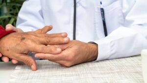 doctor examining the left hand of a person with osteoarthritis
