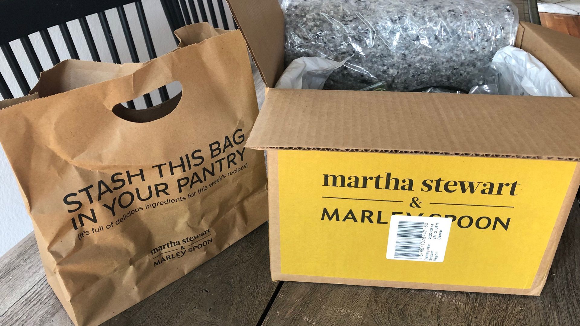 Martha and Marley Spoon delivery box open on a table with the produce bag to the side