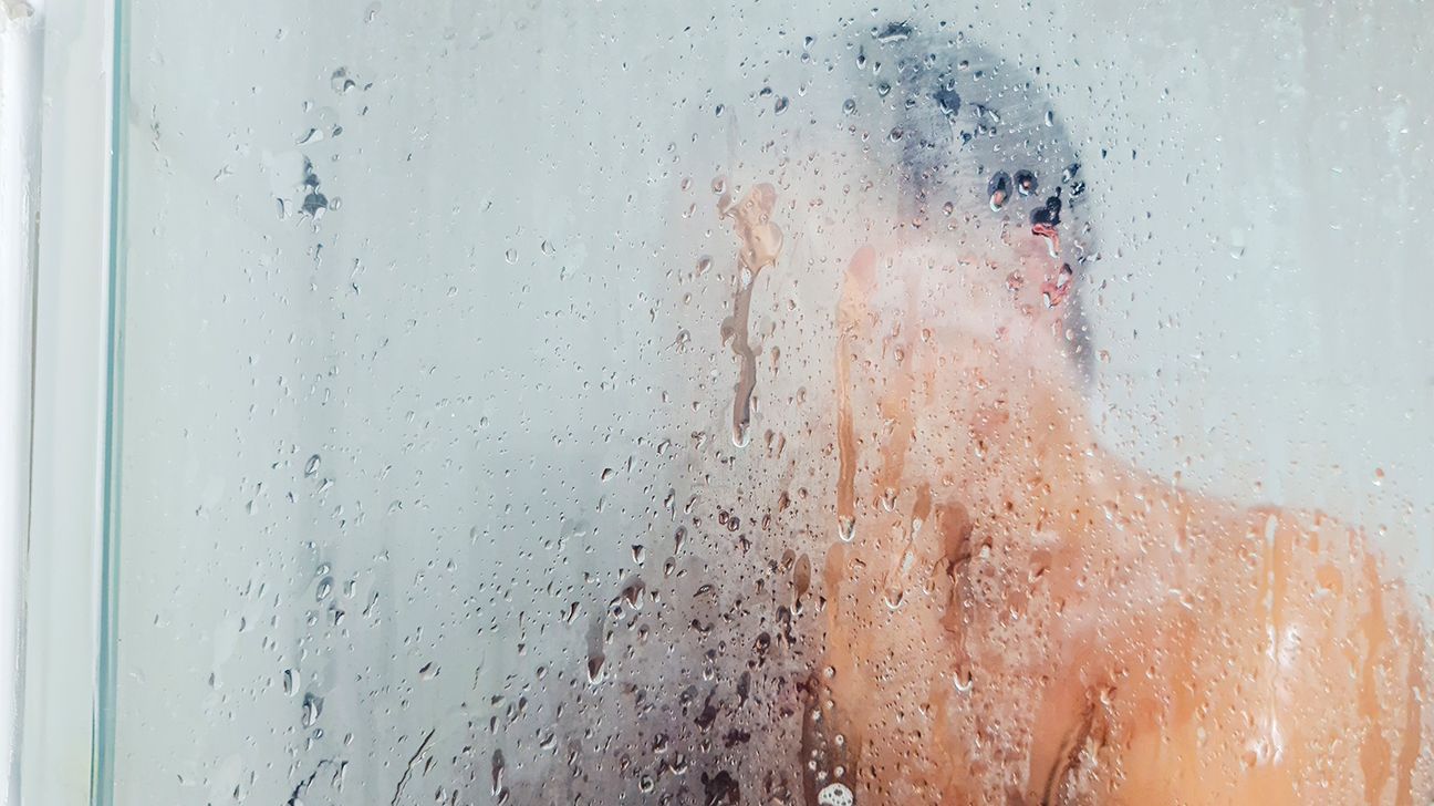 Mann i en dampende dusj.