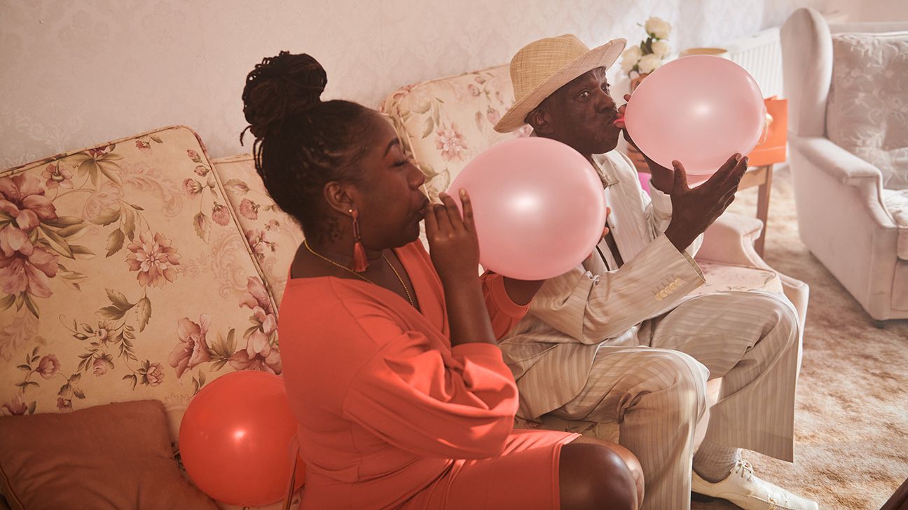 A man and a woman blow up party balloons.