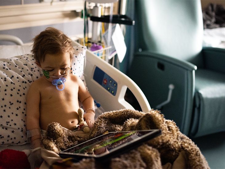 A toddler is seen in a hospital bed.