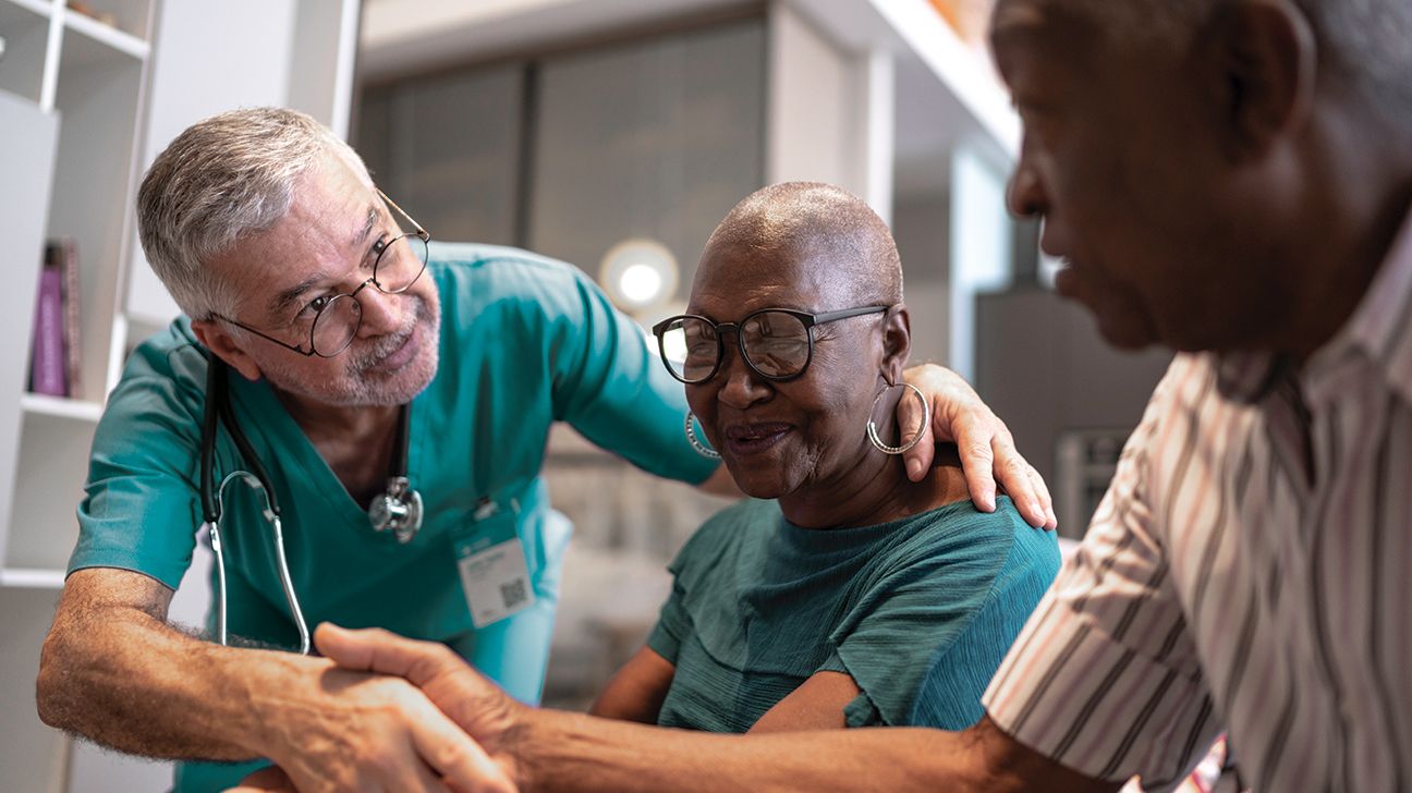 En läkare som hälsar ett äldre par för att diskutera demensvård. 