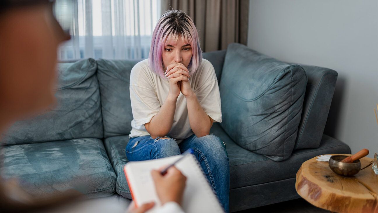 A woman in a white shirt is seen on a sofa.