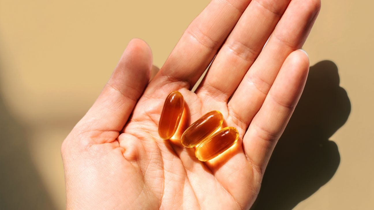 A person holds three fish oils pills.