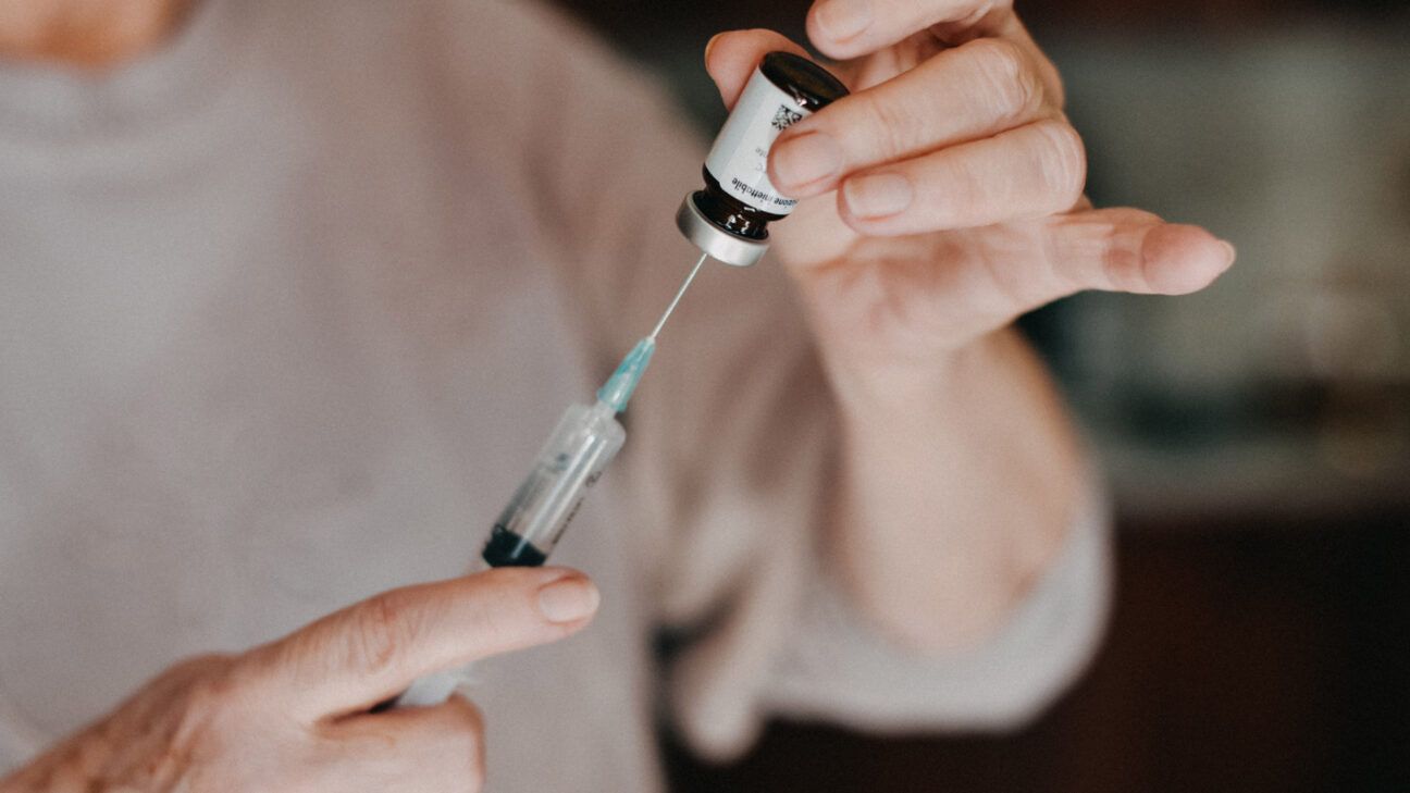 person filling a syringe with medication