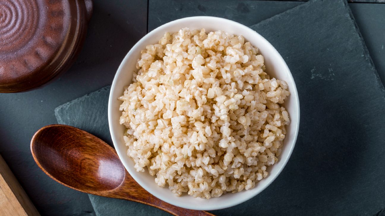 a bowl of brown rice and a wooden spoon