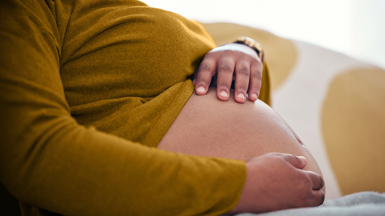 individual holding their pregnant abdomen