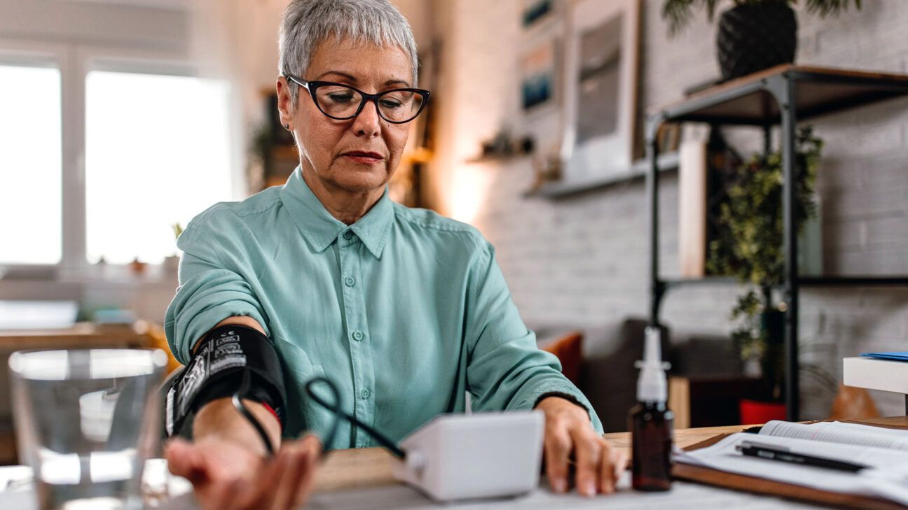 Older female checks blood pressure at home