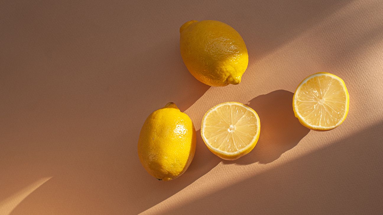 whole and cut lemons on a cutting board