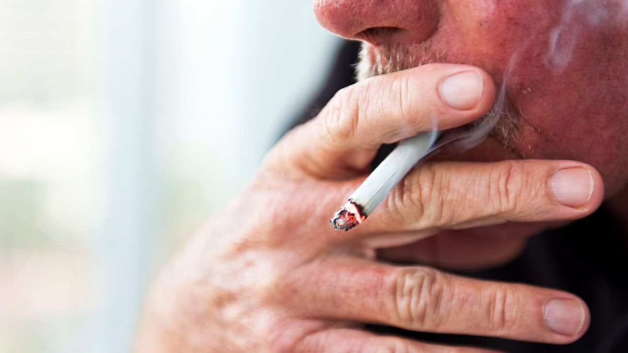 An older man puffs on a cigarette