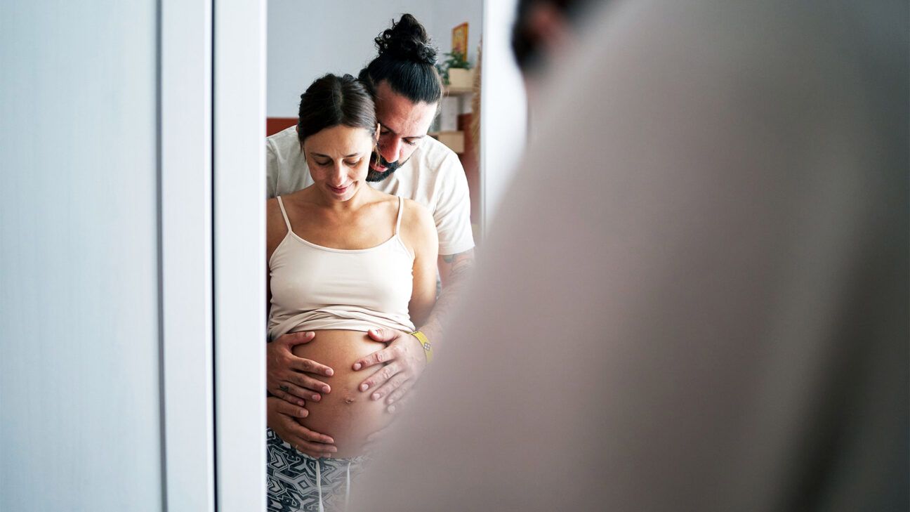 A reflection of a pregnant heterosexual couple in the mirror