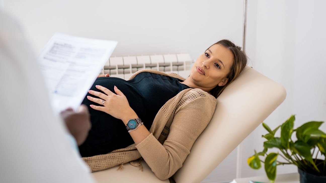 pregnant woman on exam table discussing hyperthyroidism with her doctor