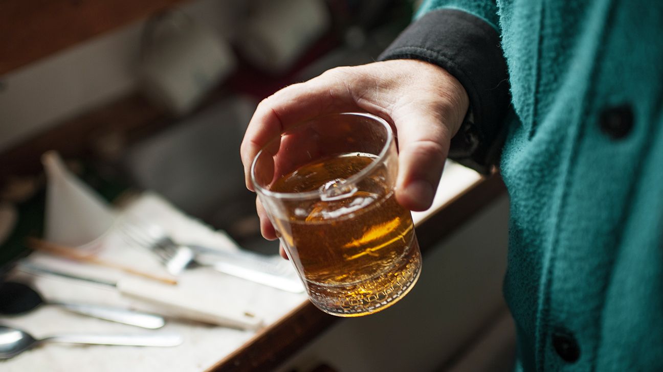 A person holding alcohol in a glass.