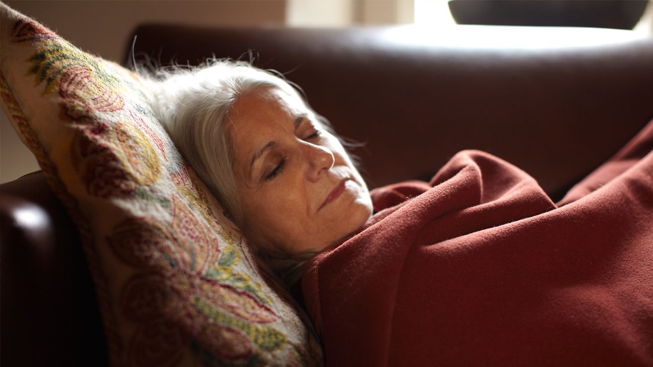 A woman takes a nap on a sofa.