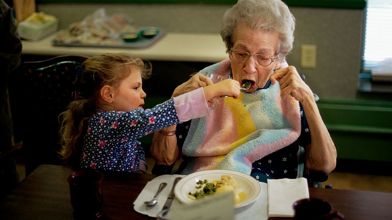 little girl feeding her grandmother who has Alzheimer's-1