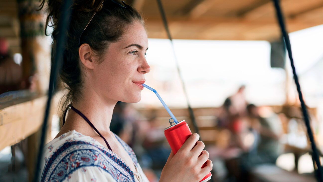 A woman drinking a beverage through a straw. 