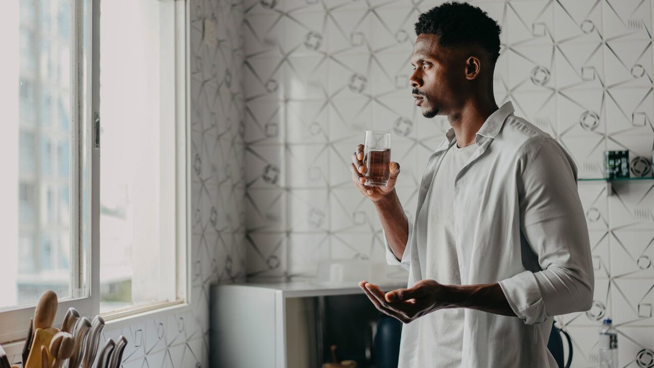 A man taking pills with water.