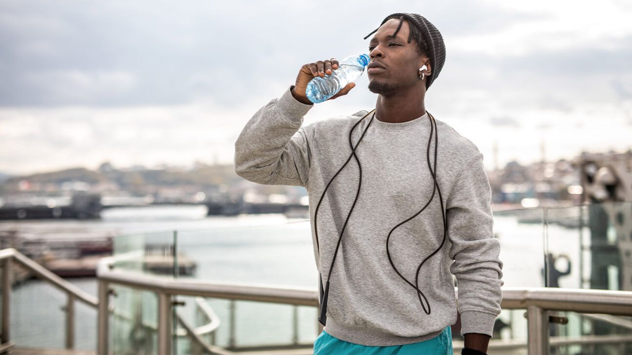 Man drinking water outside.
