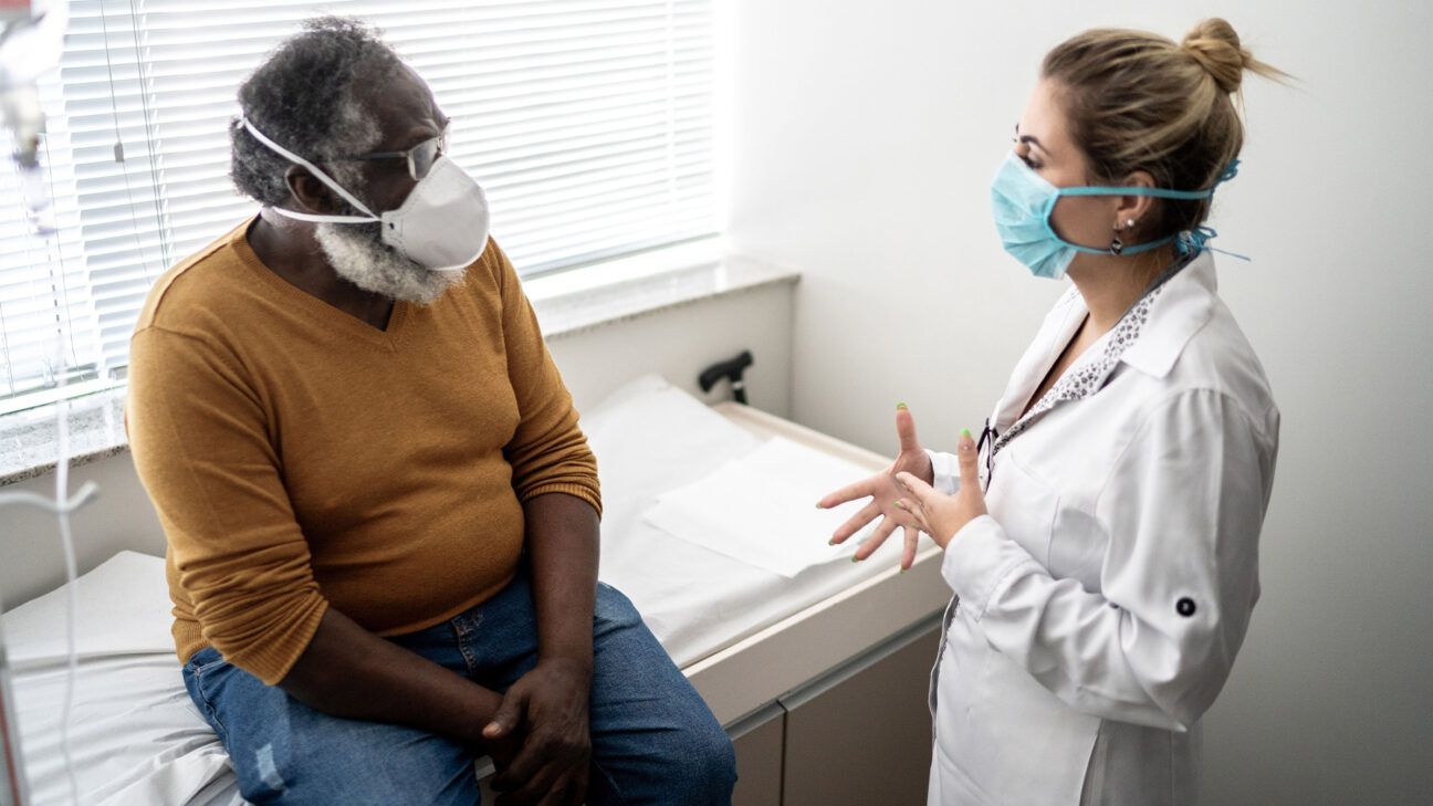 A physician talks to a patient while wearing a past.