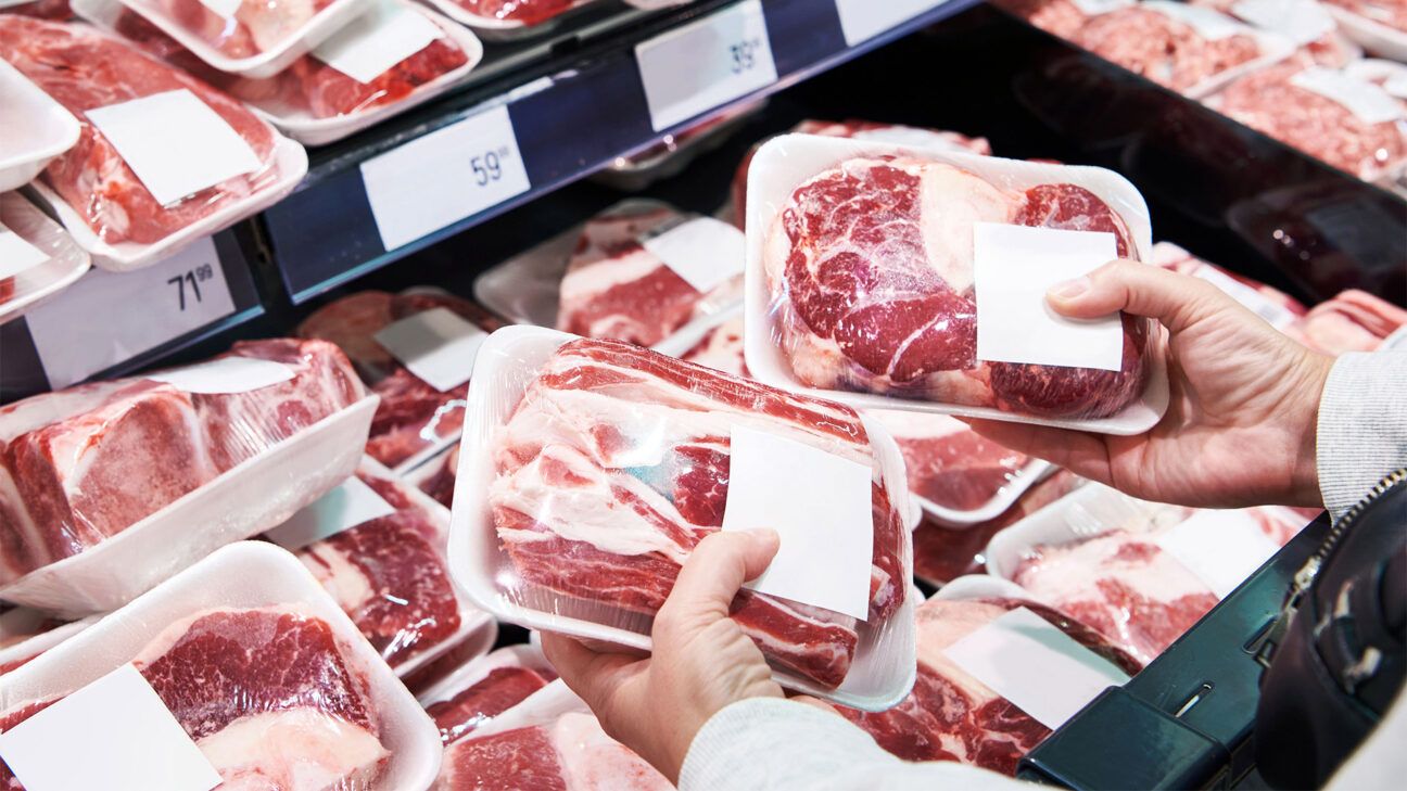 A person holding packages of red meat.