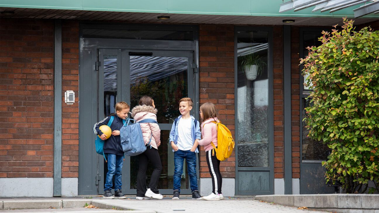 A group of kindergarteners gathers outside their school