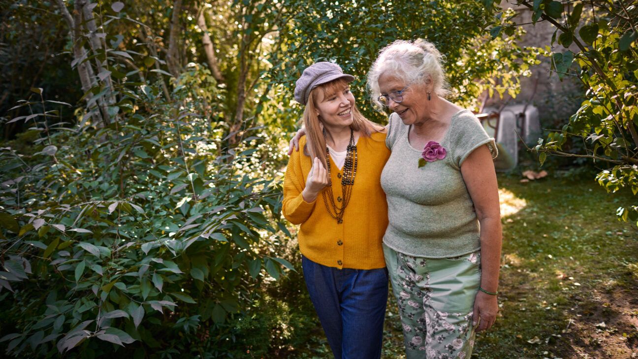 Two women are seen outside in a garden.