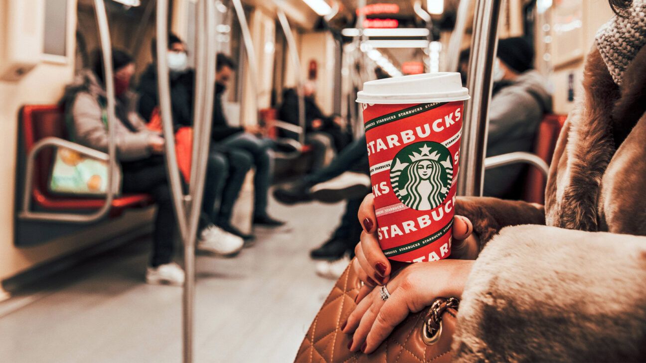 A person holding a Starbucks cup on a train.