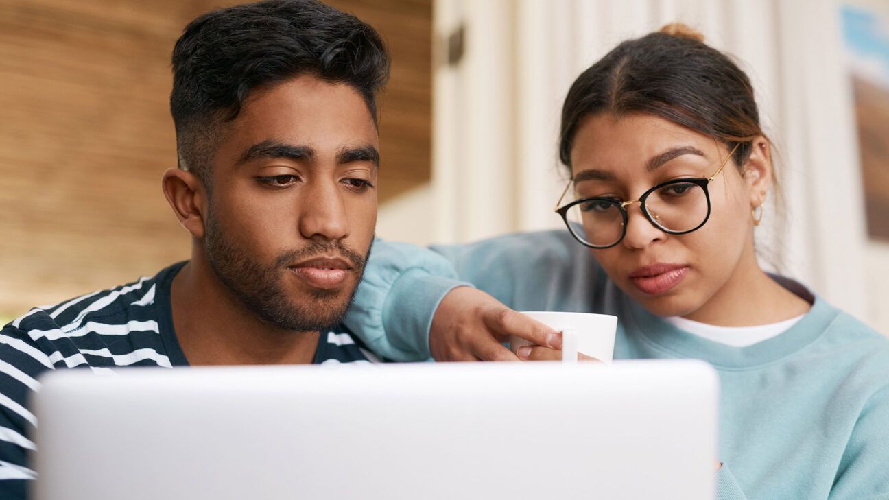 A man and woman look at a laptop together.