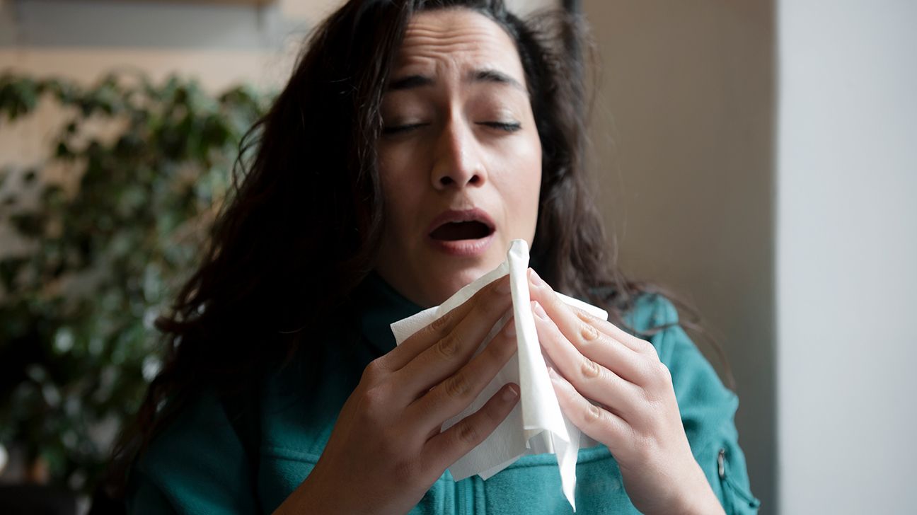 person sneezing into a tissue