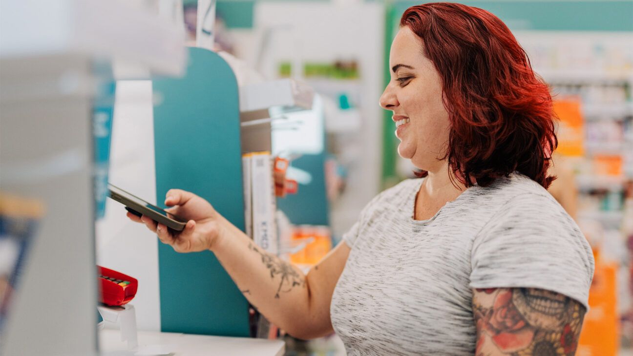 A woman paying with her phone at a pharmacy.