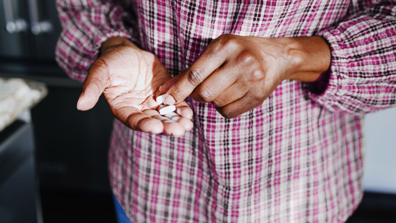 A close up of a person's hand as they pick up a pill.