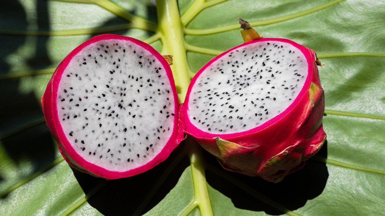 Two halves of a dragon fruit exposing the white pulp and black seeds inside