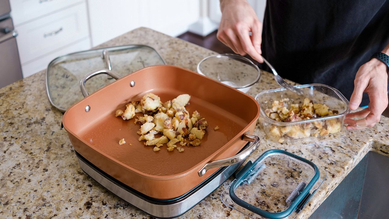 Close-up of unrecognizable white man reheating leftover potatoes in electric skillet