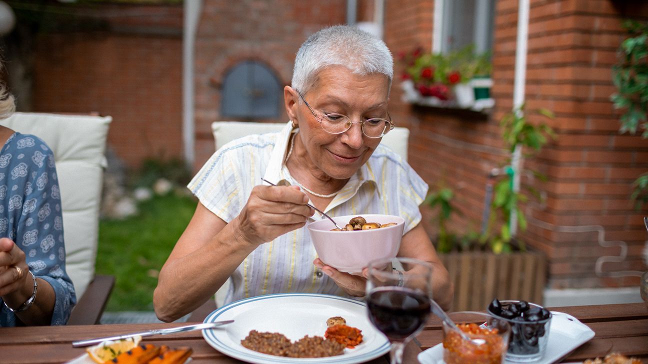 older adult enjoying a vegan lunch at an outdoor table