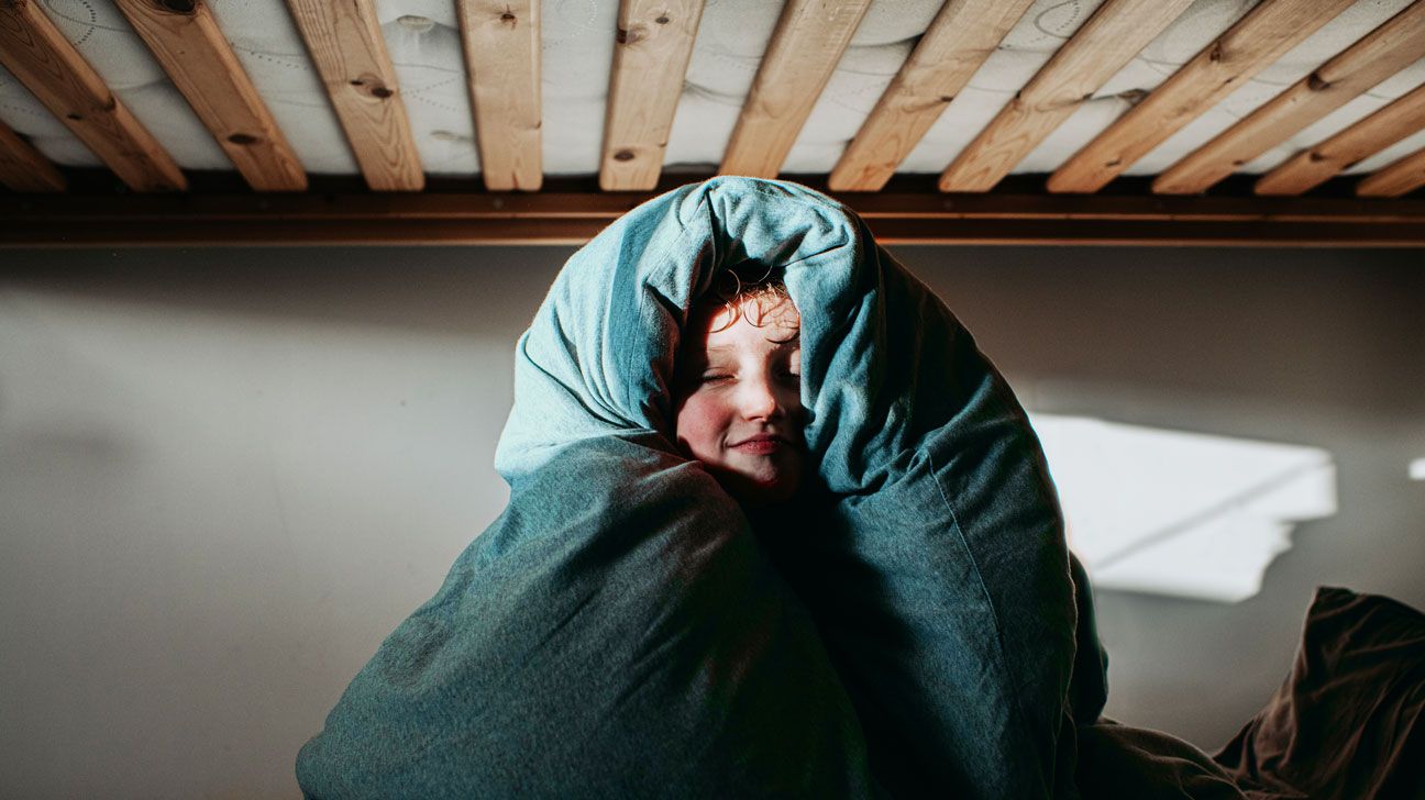 Un copil autist este somnoros învelit într-o pătură.