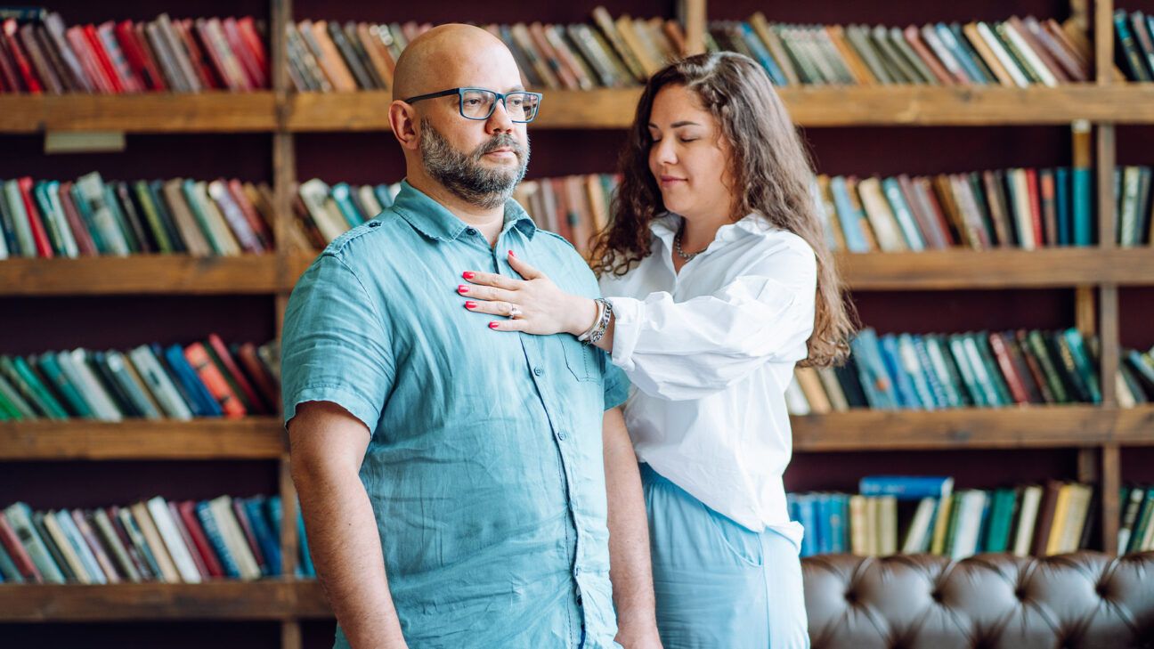 Man in blue shirt works with woman in hypnosis session.