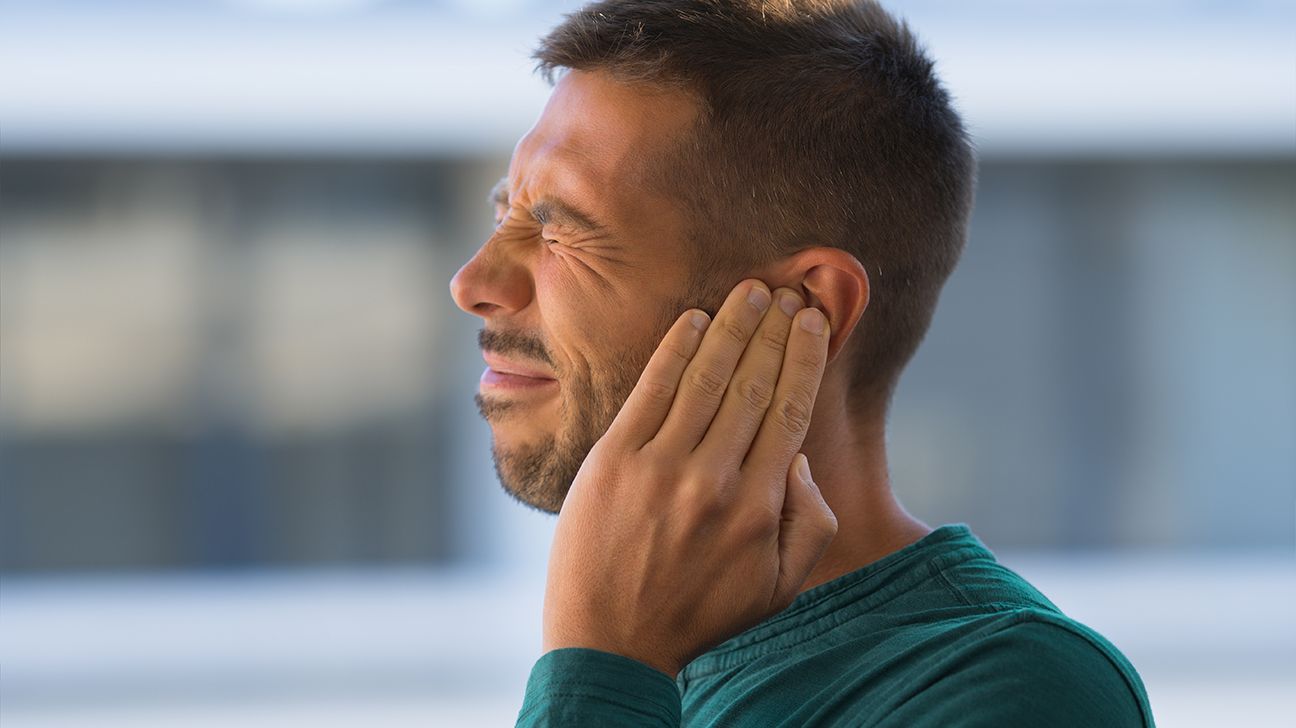 شخص بالغ يلمس أذنه بسبب طنين الأذن