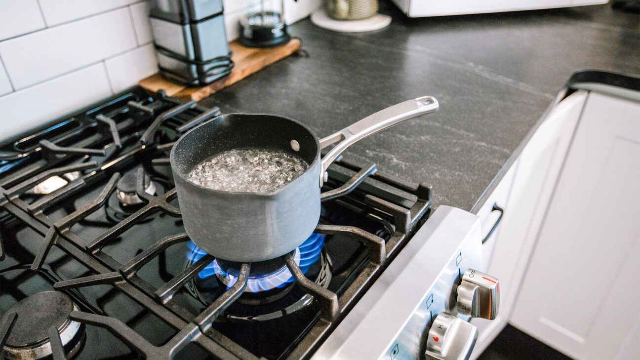 A pot of boiling water is seen on a stove