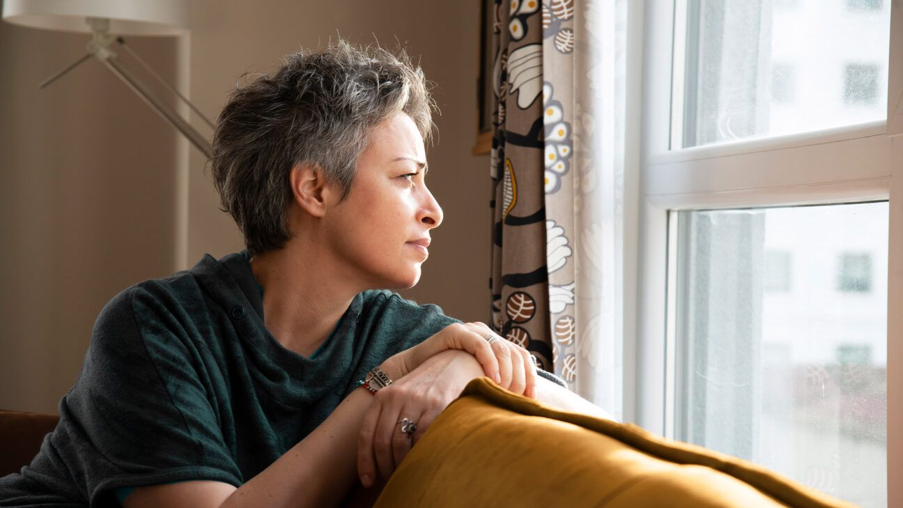 Woman with short hair looks out the window.