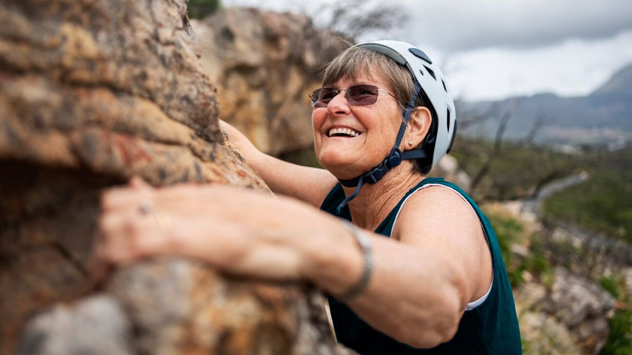 Woman smiling while climbing rockwall.