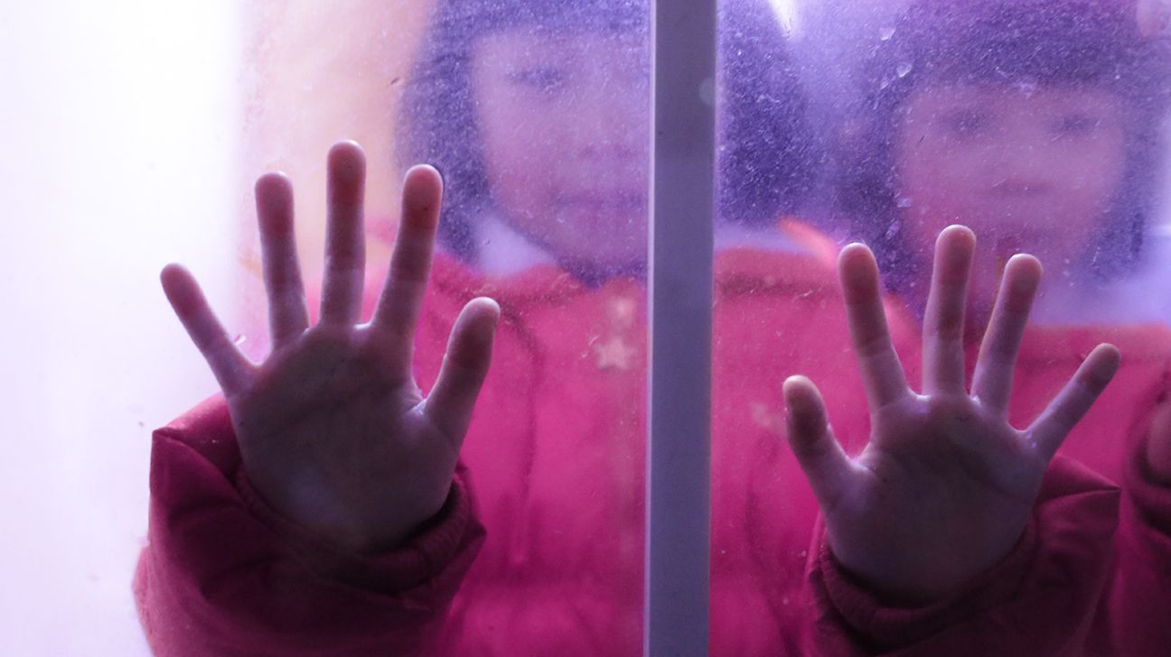 twins with their hands pressed against the other side of a glass door