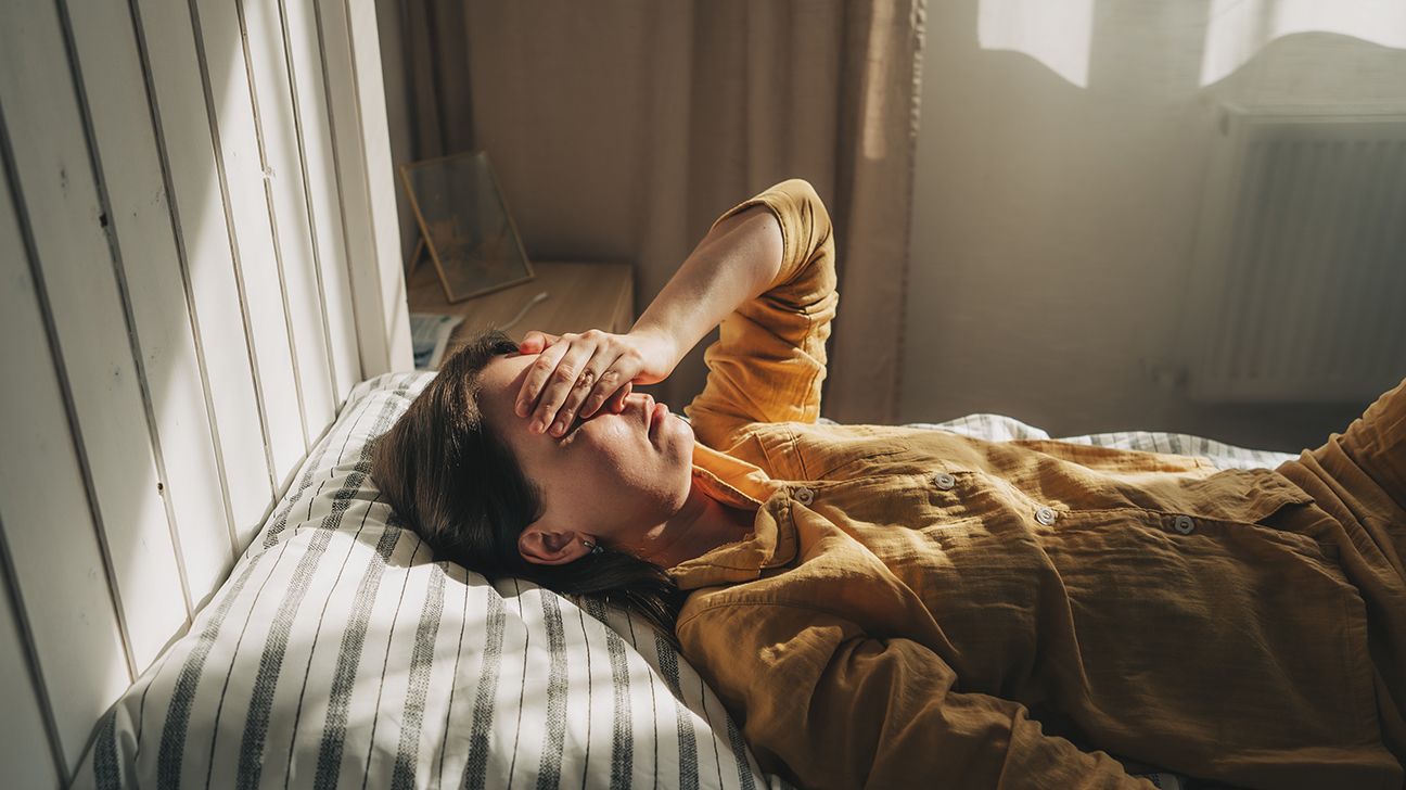 امرأة مستلقية على السرير وتبدو مرهقة